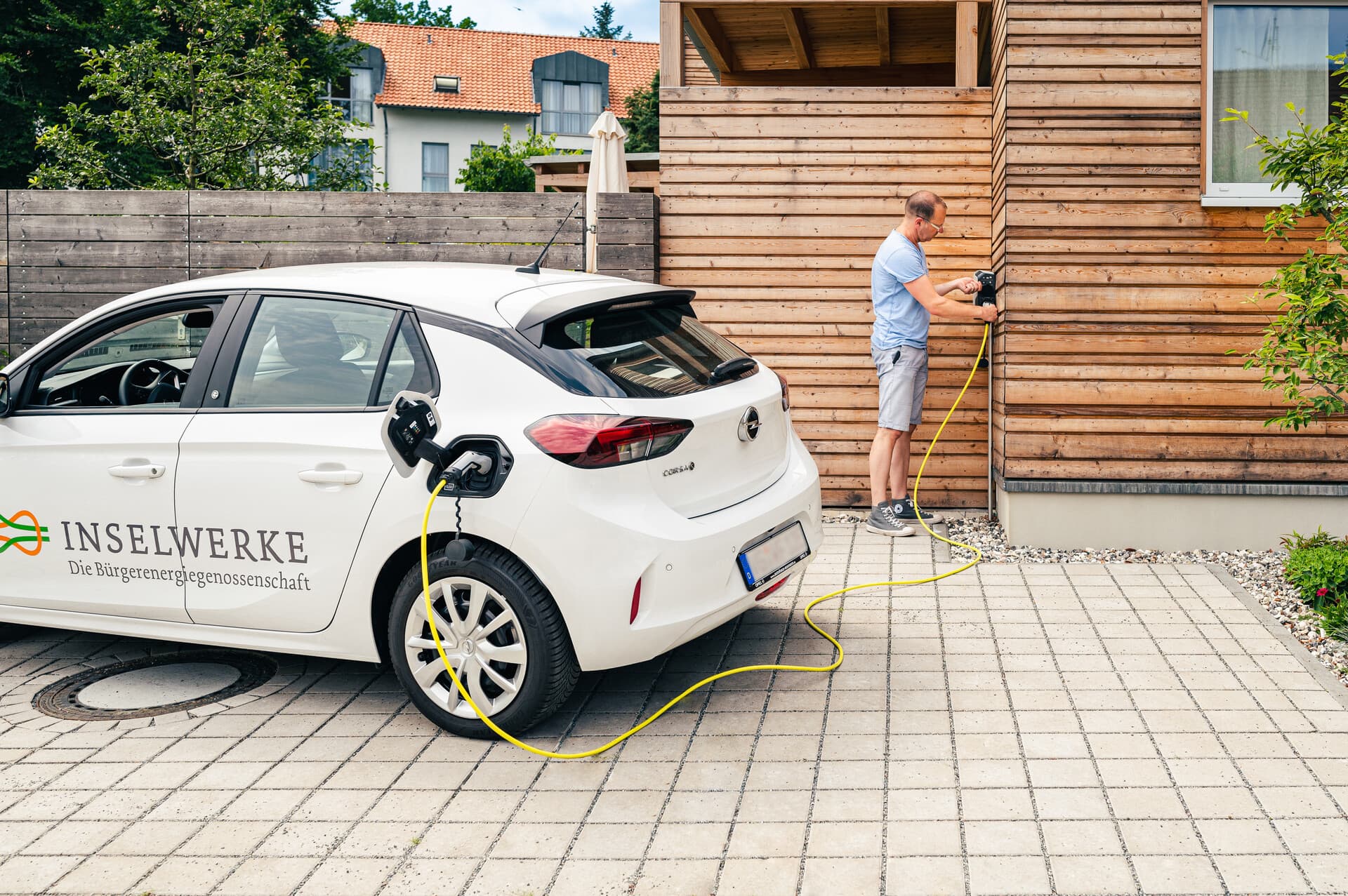 Ein Mann lädt ein E-Auto an der Ladestation eines Ferienhauses auf.