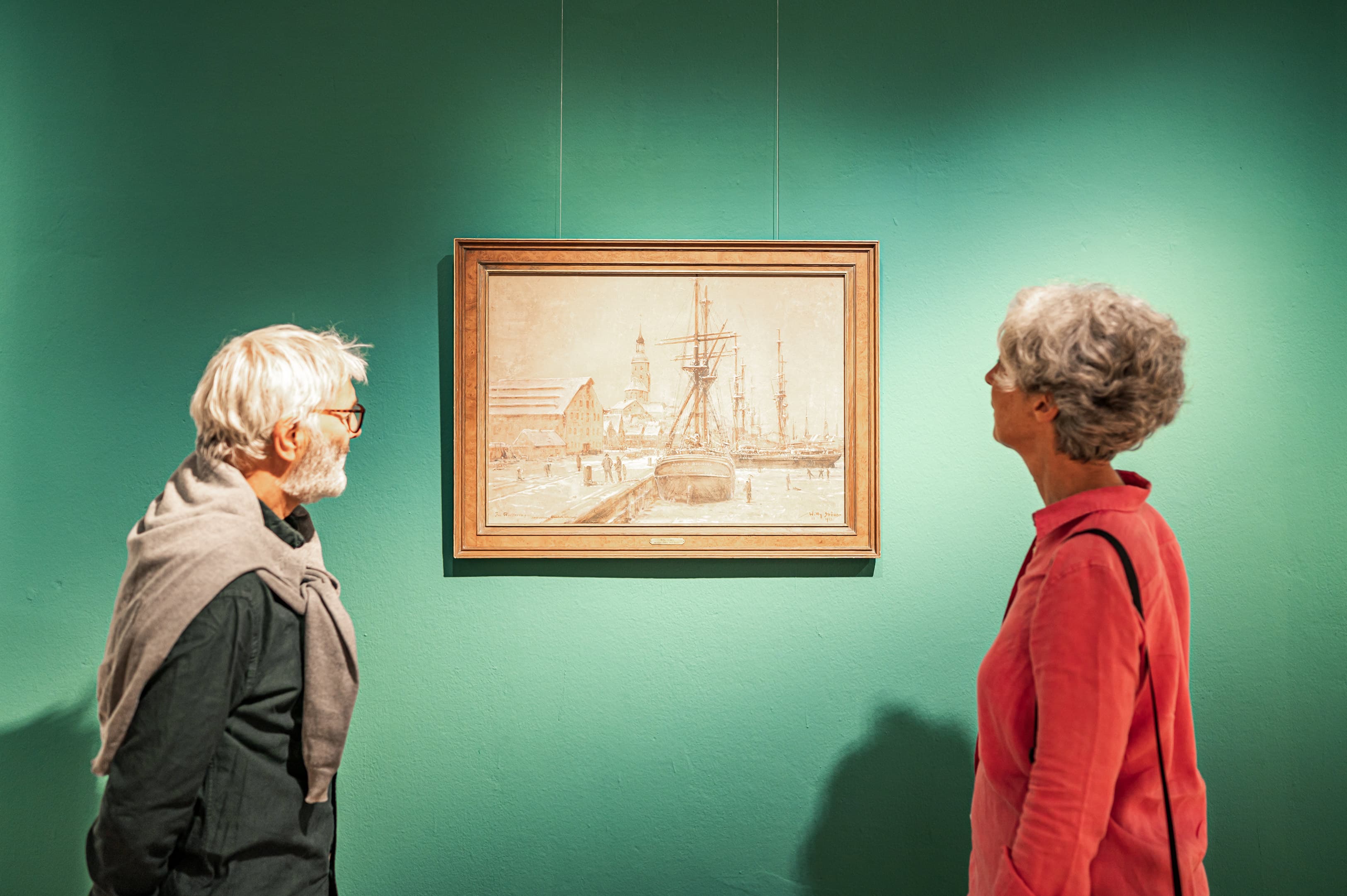Zwei Personen betrachten ein Gemälde.