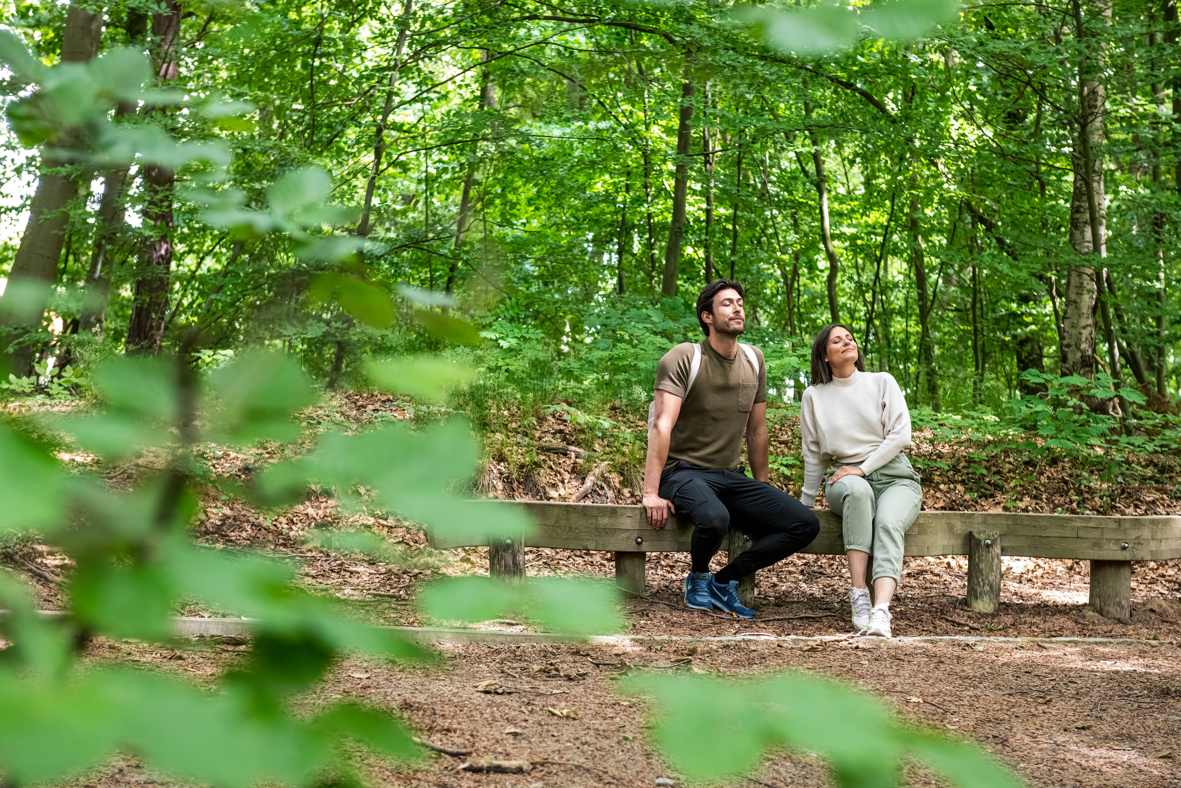 Pärchen sitzt im Wald auf einer Bank und genießt die Ruhe