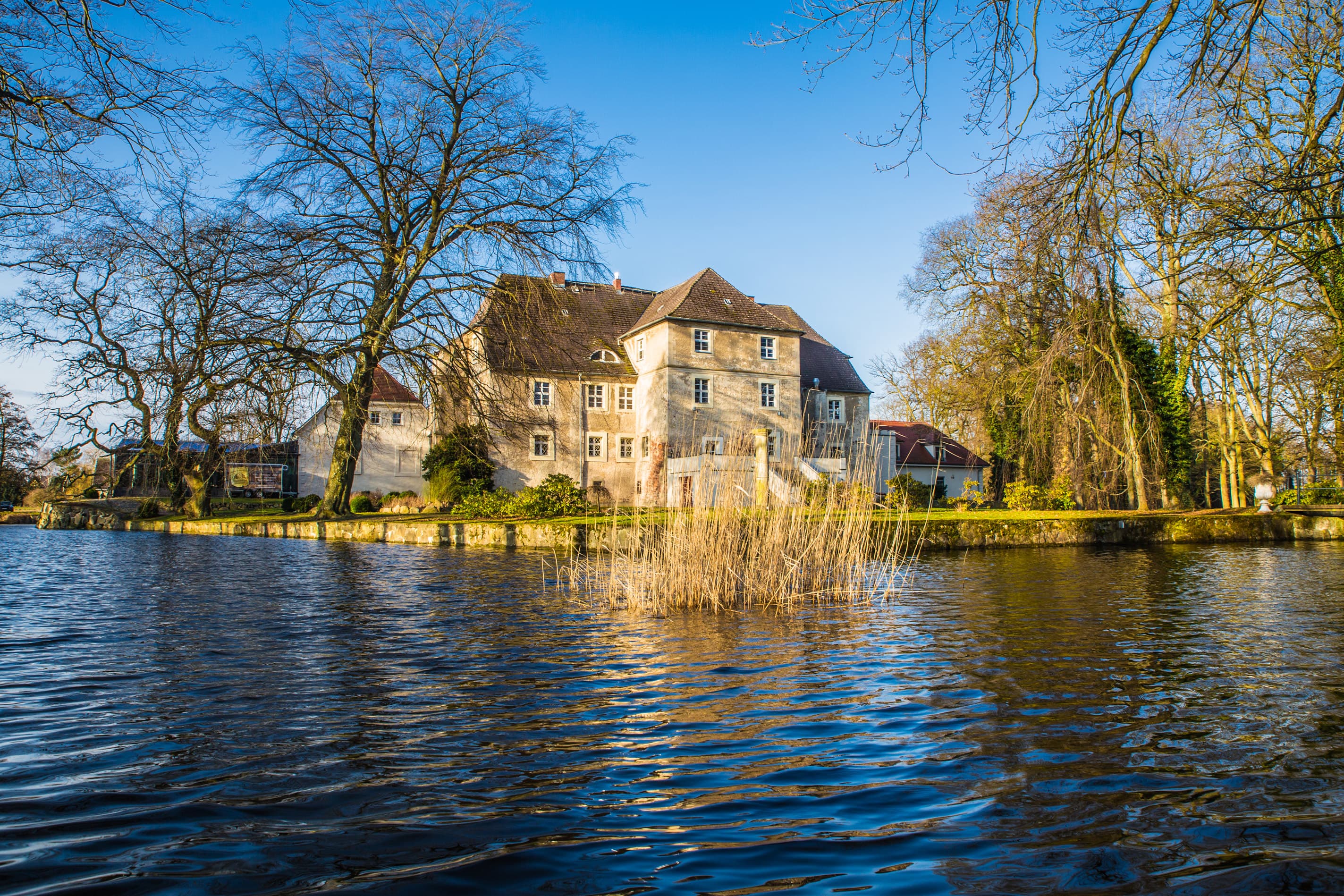 Blick über einen Teich auf das Wasserschloss Mellenthin
