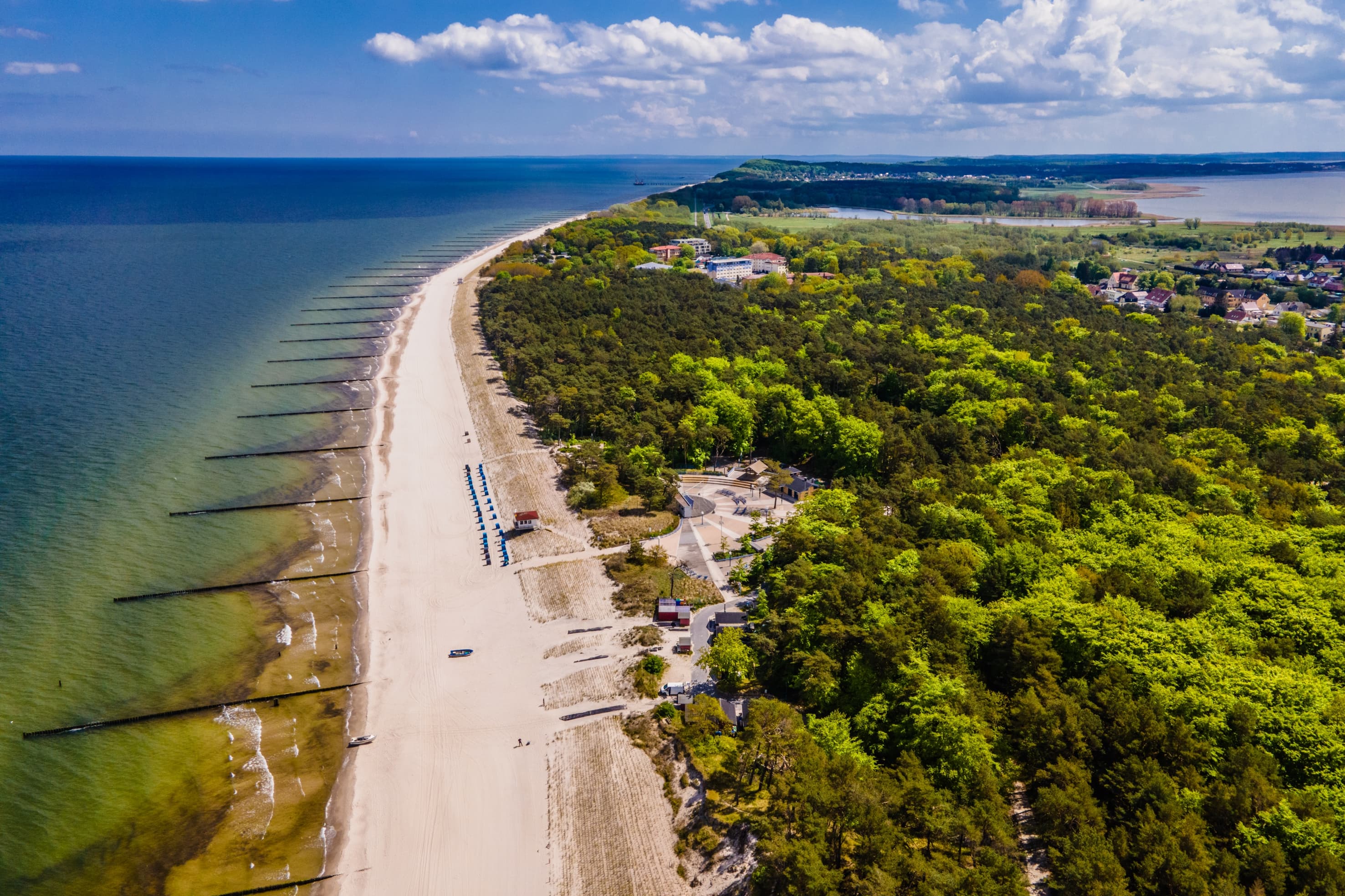 Das Foto zeigt eine Luftaufnahme des Seebades Zempin mit dem weitläufigen Strand und den grünen Küstenwäldern.