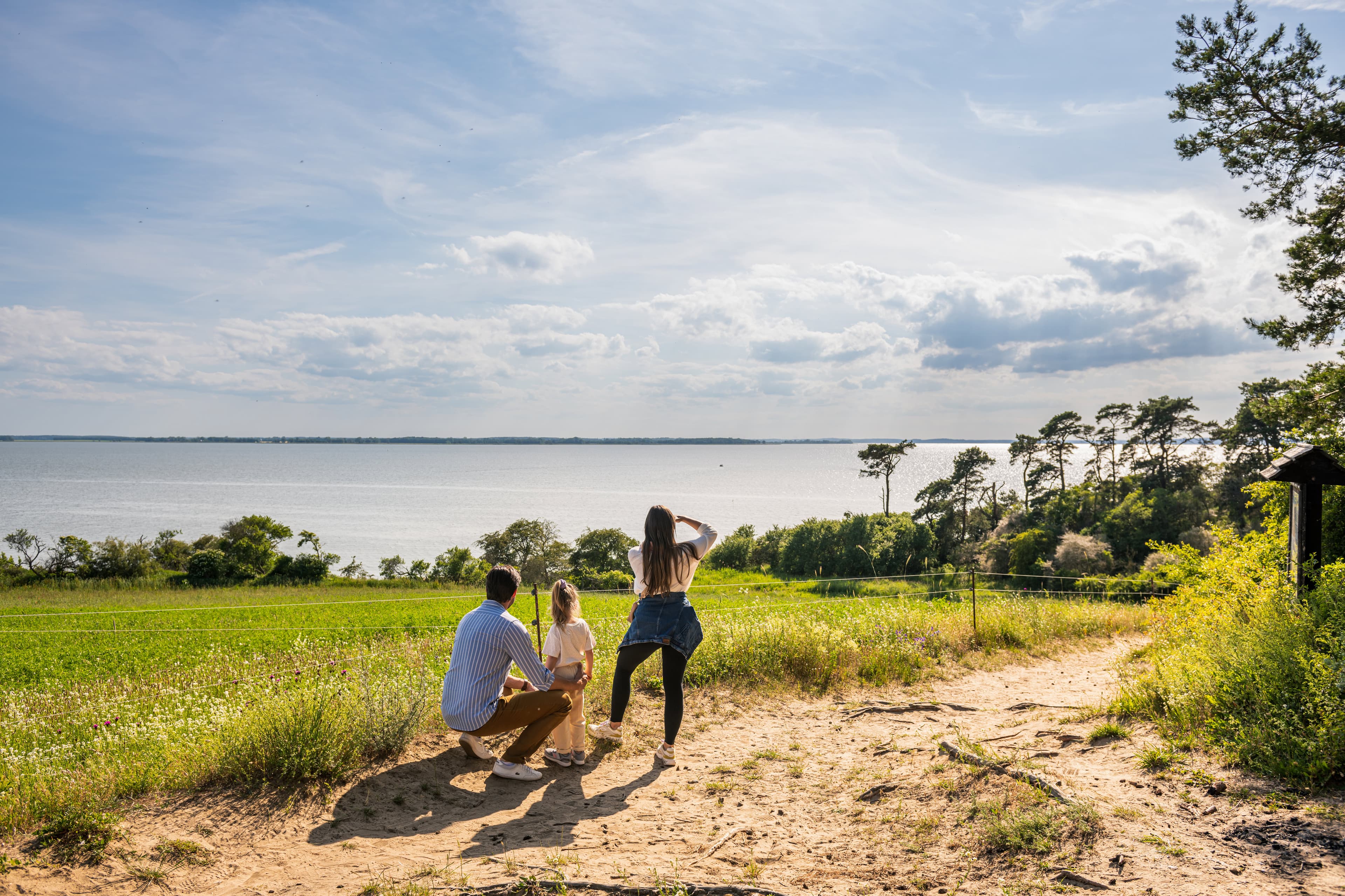 Familie steht auf einem Berg und blickt auf das Achterwasser.