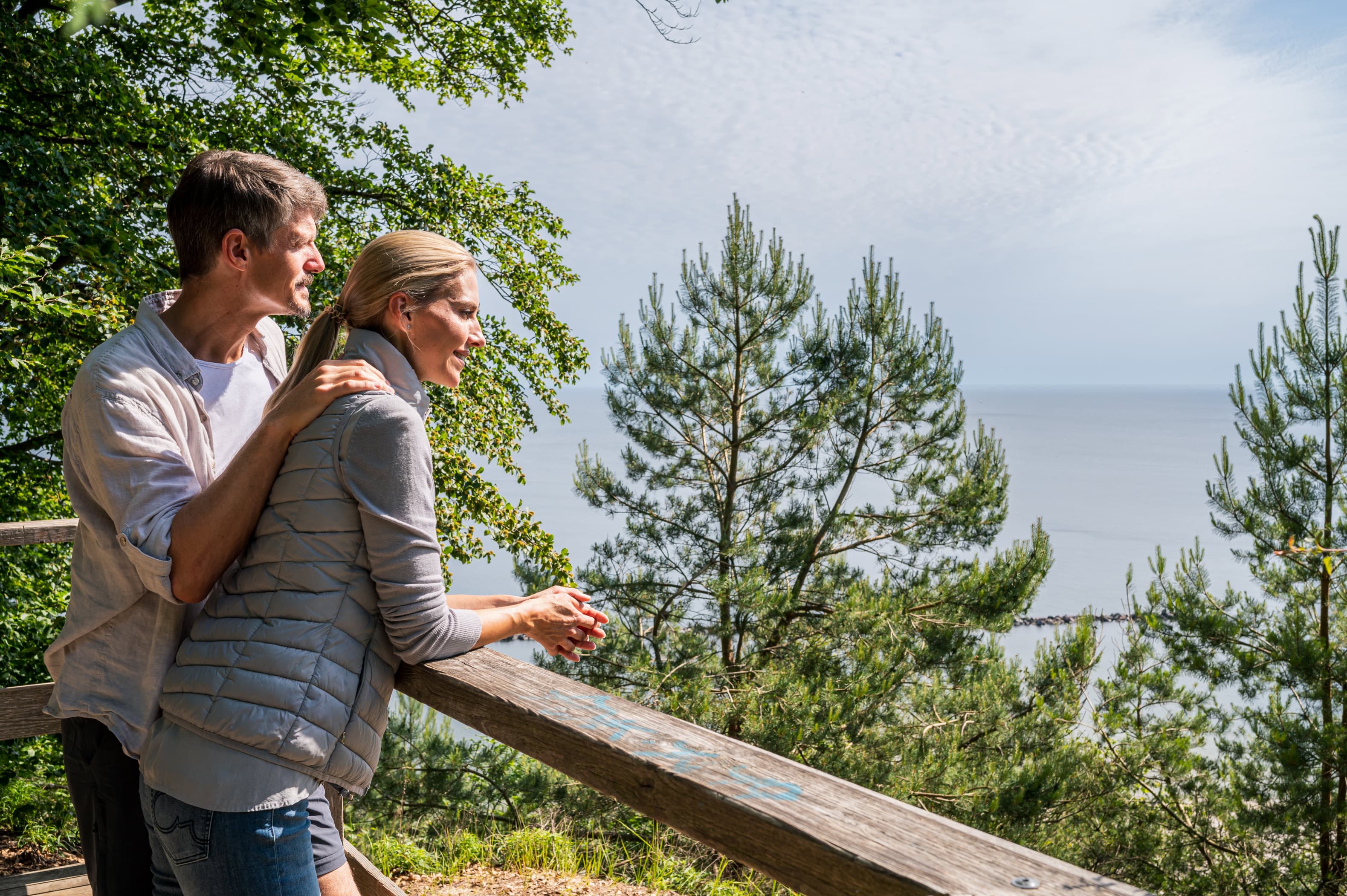 Pärchen blickt an einem Geländer auf die Ostsee.