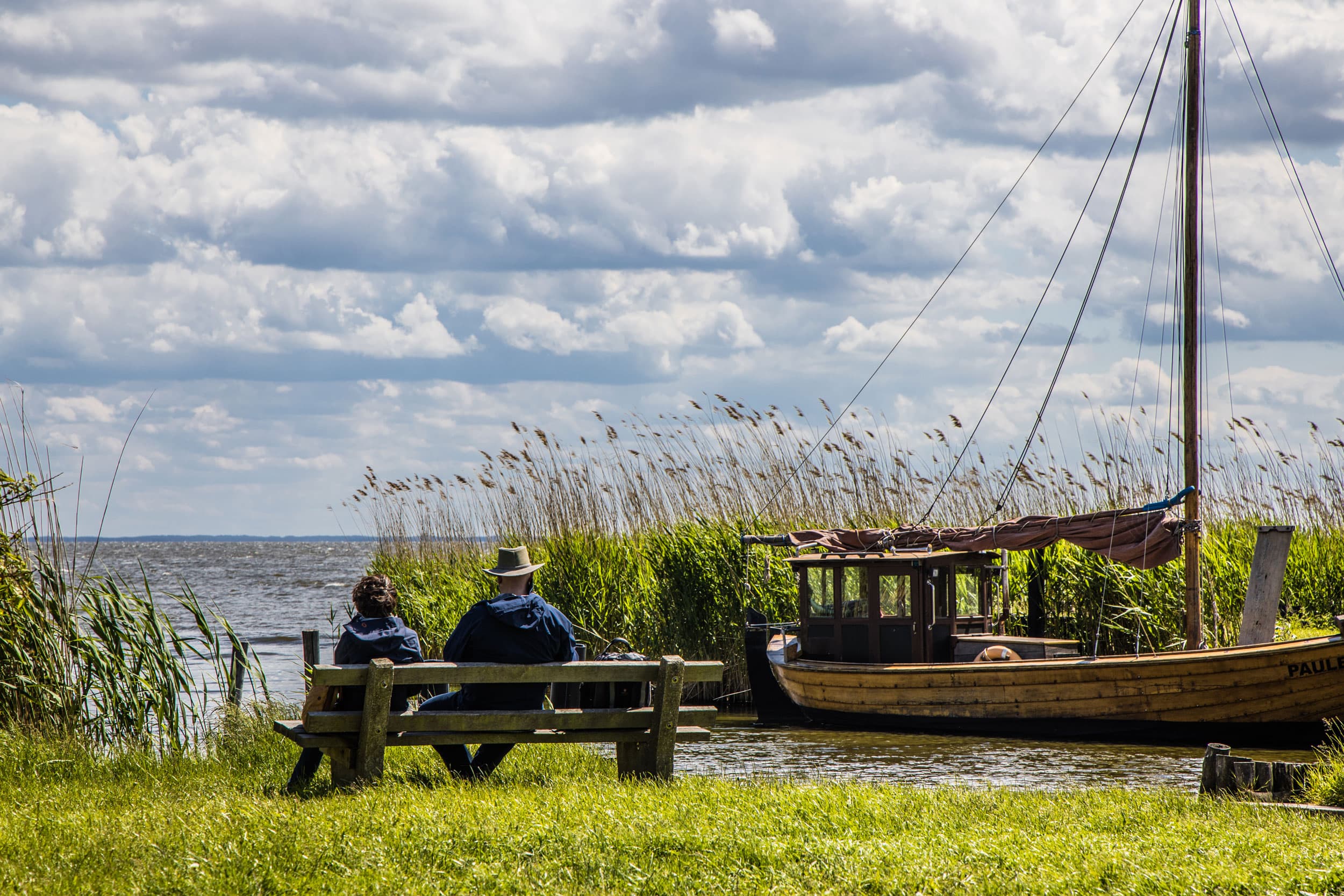Das Bild zeigt ein Pärchen auf einer Bank im kleinen Hafen in Gummlin am Stettiner Haff.